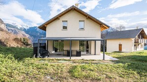 Une maison moderne dotée d’un patio couvert, d’un garage et offrant une vue sur les montagnes.