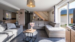 Un salon moderne avec un canapé d’angle, une table basse et une grande fenêtre.