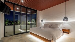 A modern bedroom with a large bed, a sliding glass door leading to a balcony, and pendant lighting. - Villa Nuusa Bingin (Pecatu)