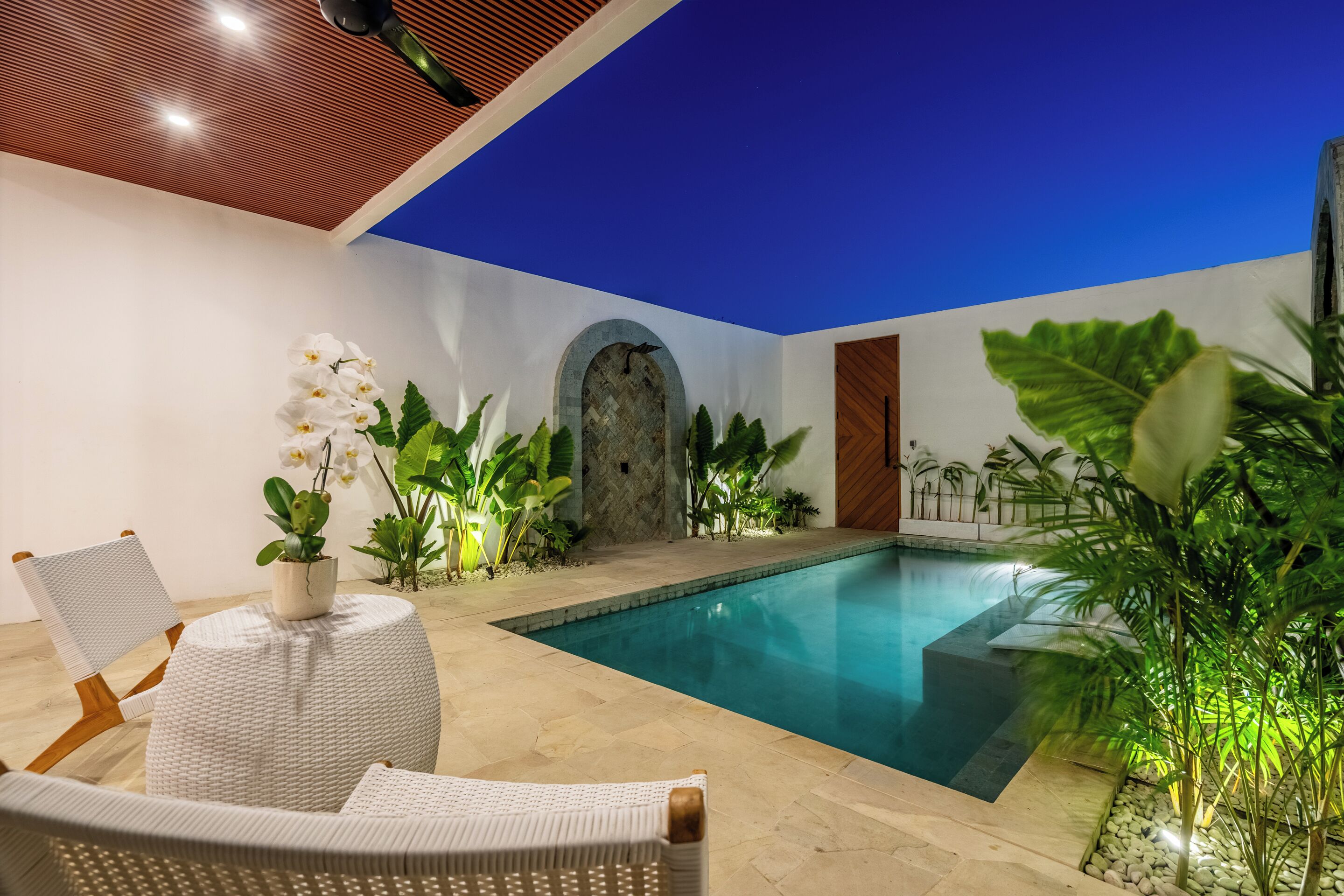 Zona de piscina con vista despejada, una silla y plantas circundantes.