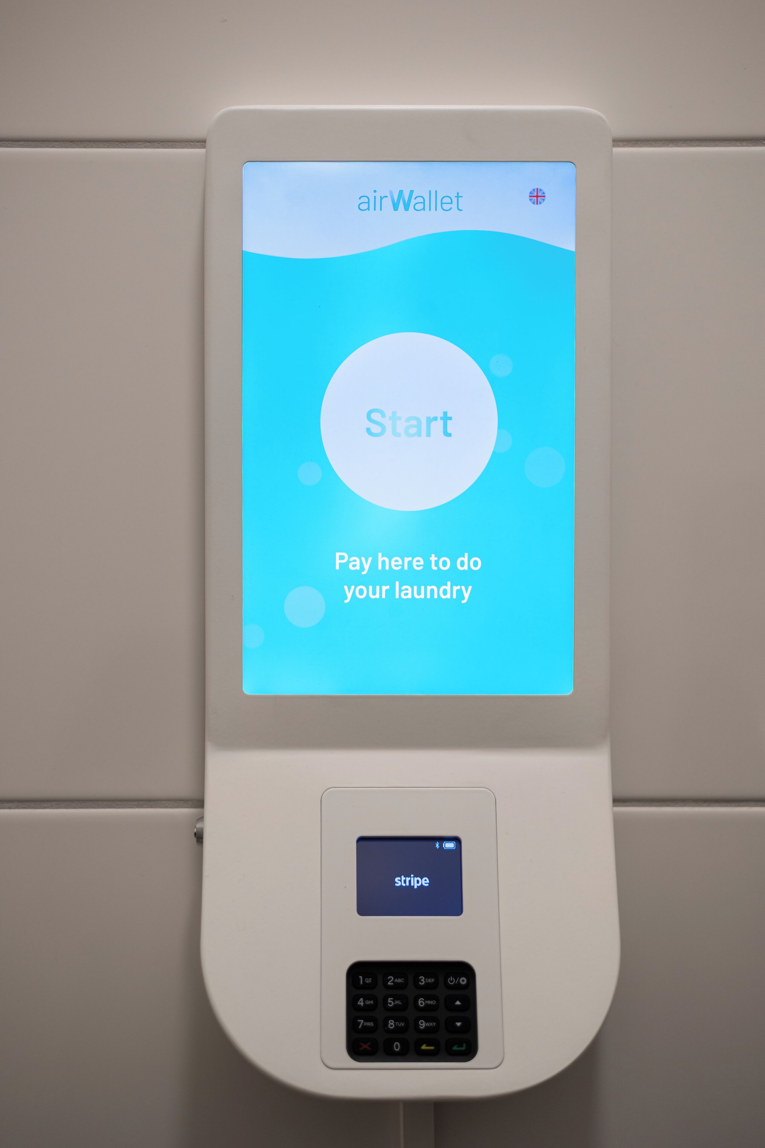 A wall-mounted air wallet with a screen displaying 'Start Pay here to do your laundry' and a keypad below it.