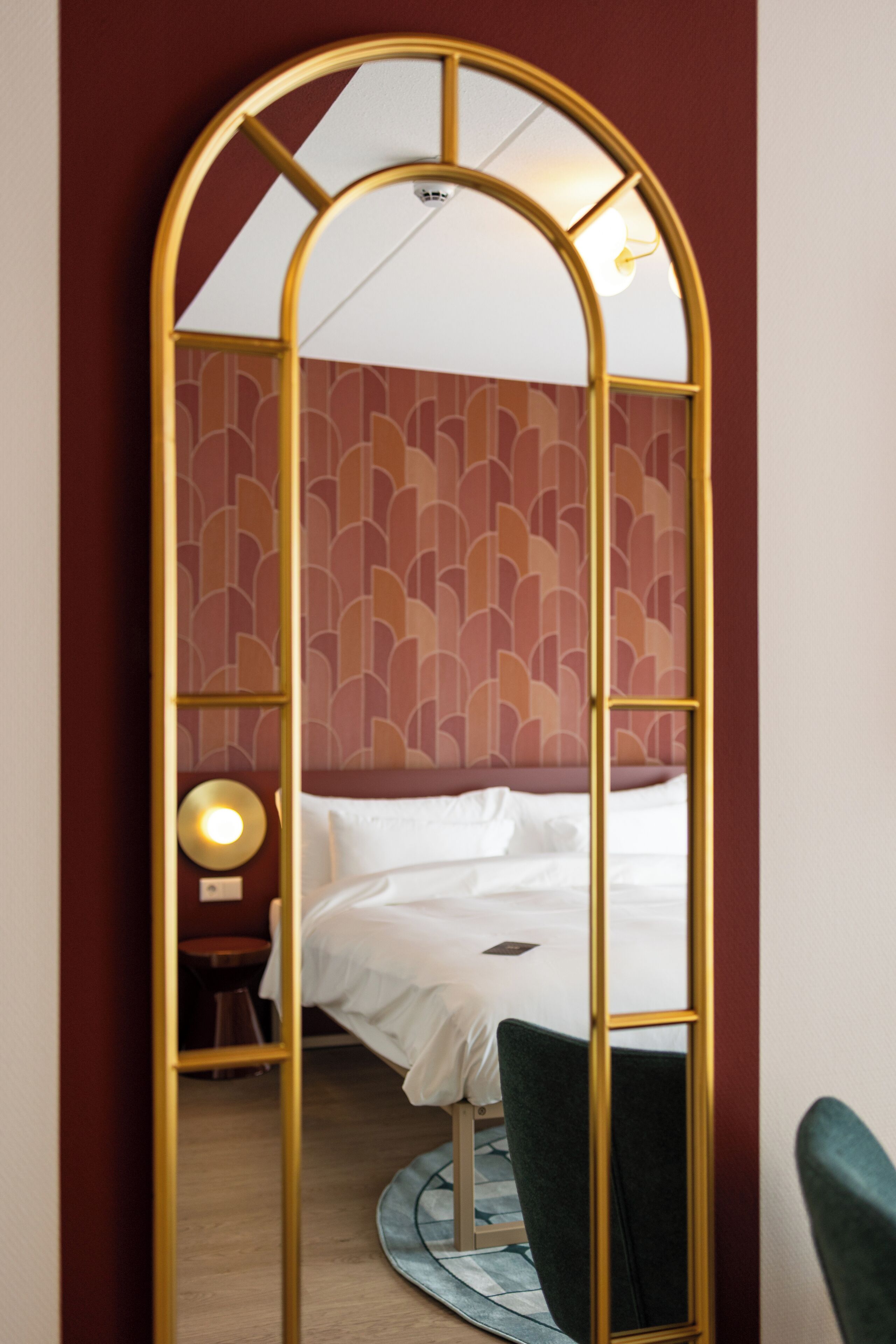 Una habitación de hotel con una cama, una mesa redonda, una silla y un espejo con marco dorado.