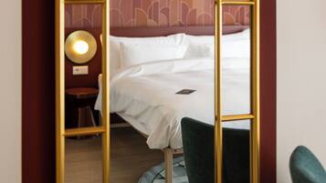 Una habitación de hotel con una cama, una mesa redonda, una silla y un espejo con marco dorado.
