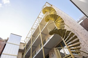 A multi-story building with a spiral staircase and a metal railing. - Duke Studio Hotel ('s-Hertogenbosch)