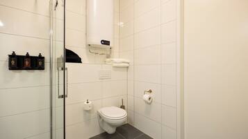 A modern bathroom with a glass shower enclosure, a white toilet, a towel rack, and a toilet paper holder.