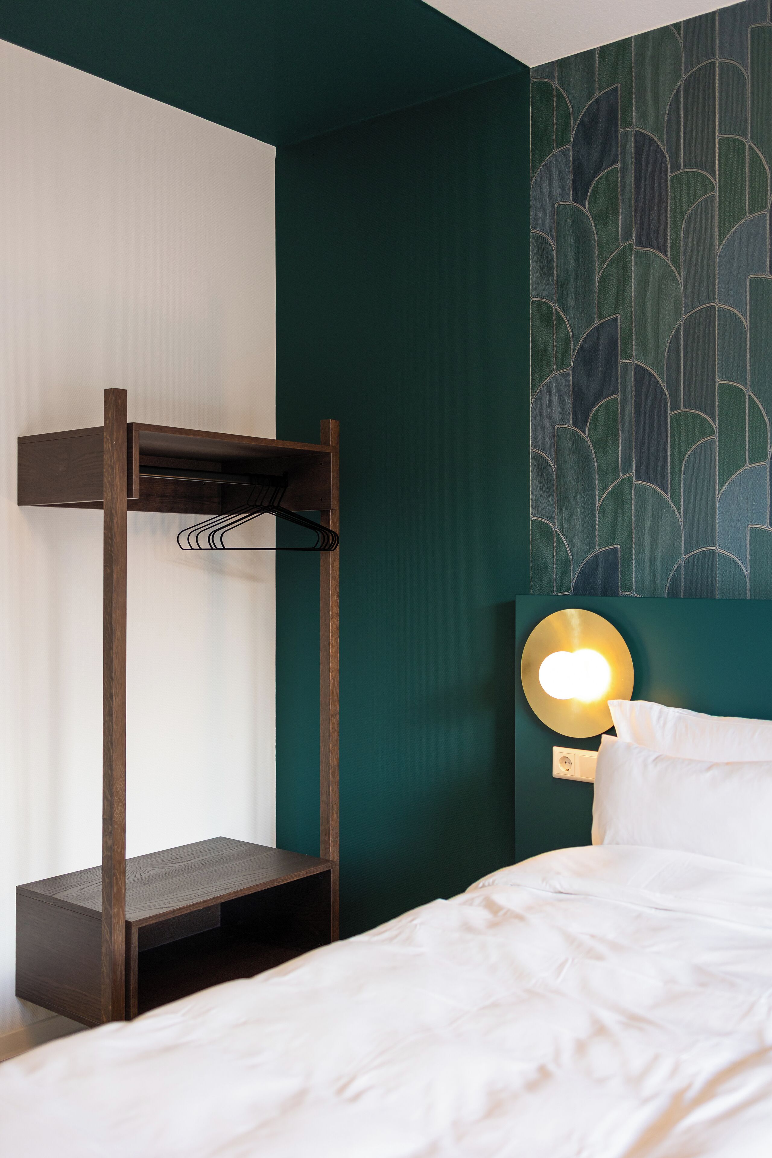 Ein Zimmer mit einem Etagenbett, einem Nachttisch, einer Wandlampe und einer Wand mit Muster.