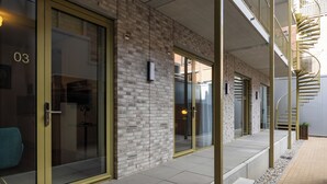 A modern building with glass doors, a brick facade, and a spiral staircase. - Duke Studio Hotel ('s-Hertogenbosch)