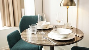 A dining table with a modern lamp, a green chair, and a television mounted on the wall. - Duke Studio Hotel ('s-Hertogenbosch)