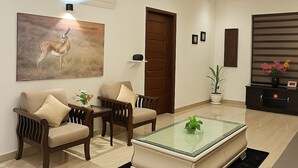 A modern living room with a glass-top coffee table, two sofas, a wooden cabinet, and a painting of a deer. - Let'stay- Aerocity Mohali  (Mohali)