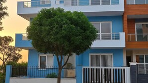 A modern multi-story residential building with balconies and a tree in the foreground. - Let'stay- Aerocity Mohali  (Mohali)