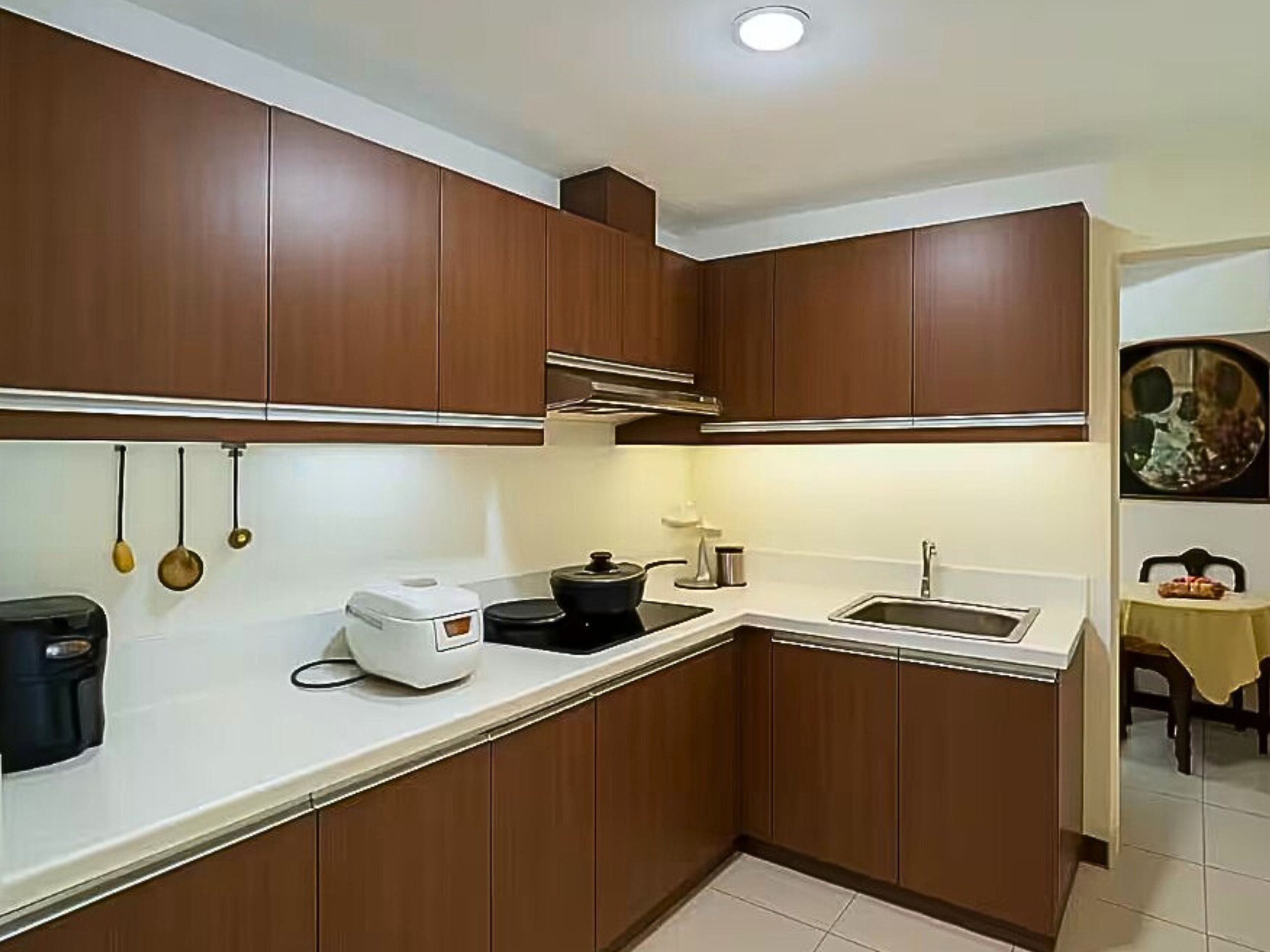 A compact kitchen with wooden cabinets, a white countertop, a sink, and a coffee maker.