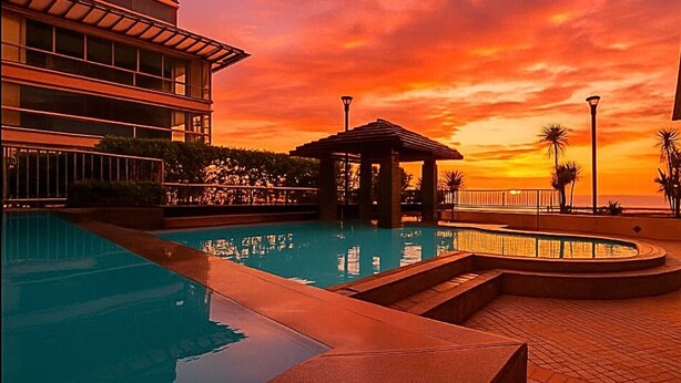 A swimming pool with a sunset view, a gazebo, and a building with multiple floors. - Seaside Escape in Front of US Embassy (Manila)