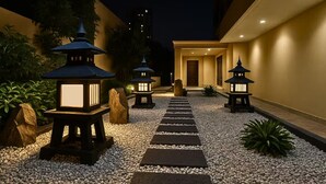 A pathway leading to a building entrance, flanked by lanterns and rocks. - Seaside Escape in Front of US Embassy (Manila)