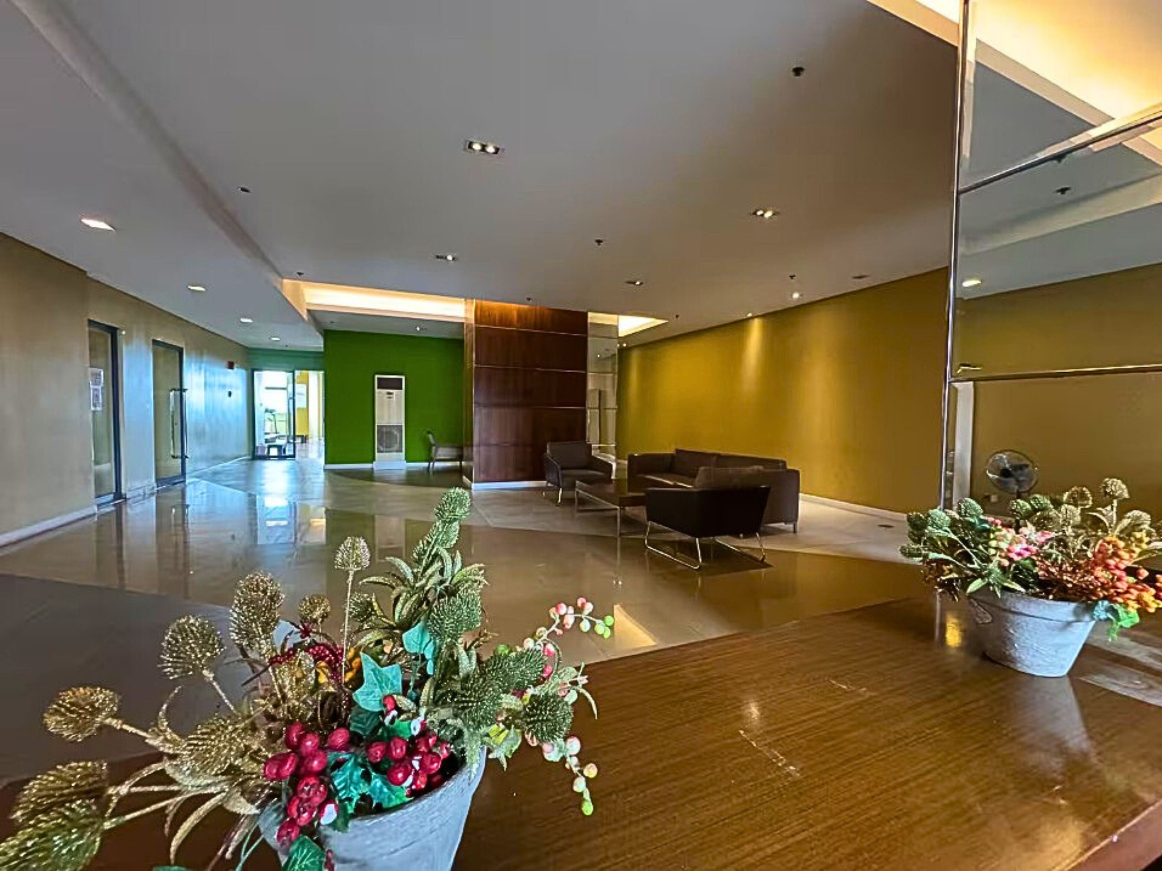 A spacious lobby with a green wall, a reception desk, and a seating area.