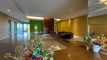 A spacious lobby with a green wall, a reception desk, and a seating area.