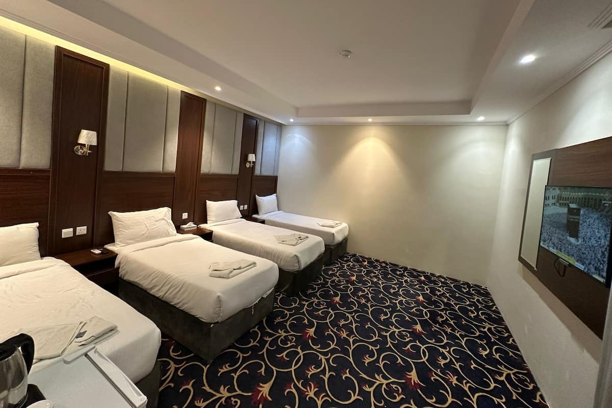 A hotel room with three beds, a large window, and a carpeted floor.