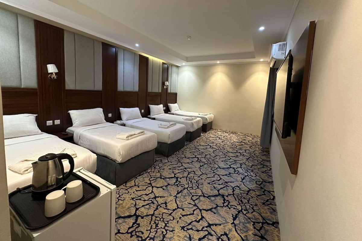 A hotel room with four beds, a coffee maker, two mugs, and a tray.