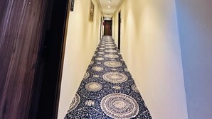A hotel hallway with patterned carpet, wooden doors, and a blue ceiling light. - Manasik Al Bait Hotel Makkah (Makkah)