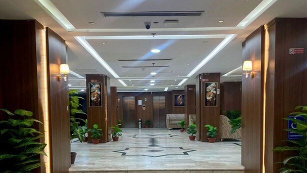 A hotel lobby with marble flooring, wooden paneling, and potted plants. - Manasik Al Bait Hotel Makkah (Makkah)