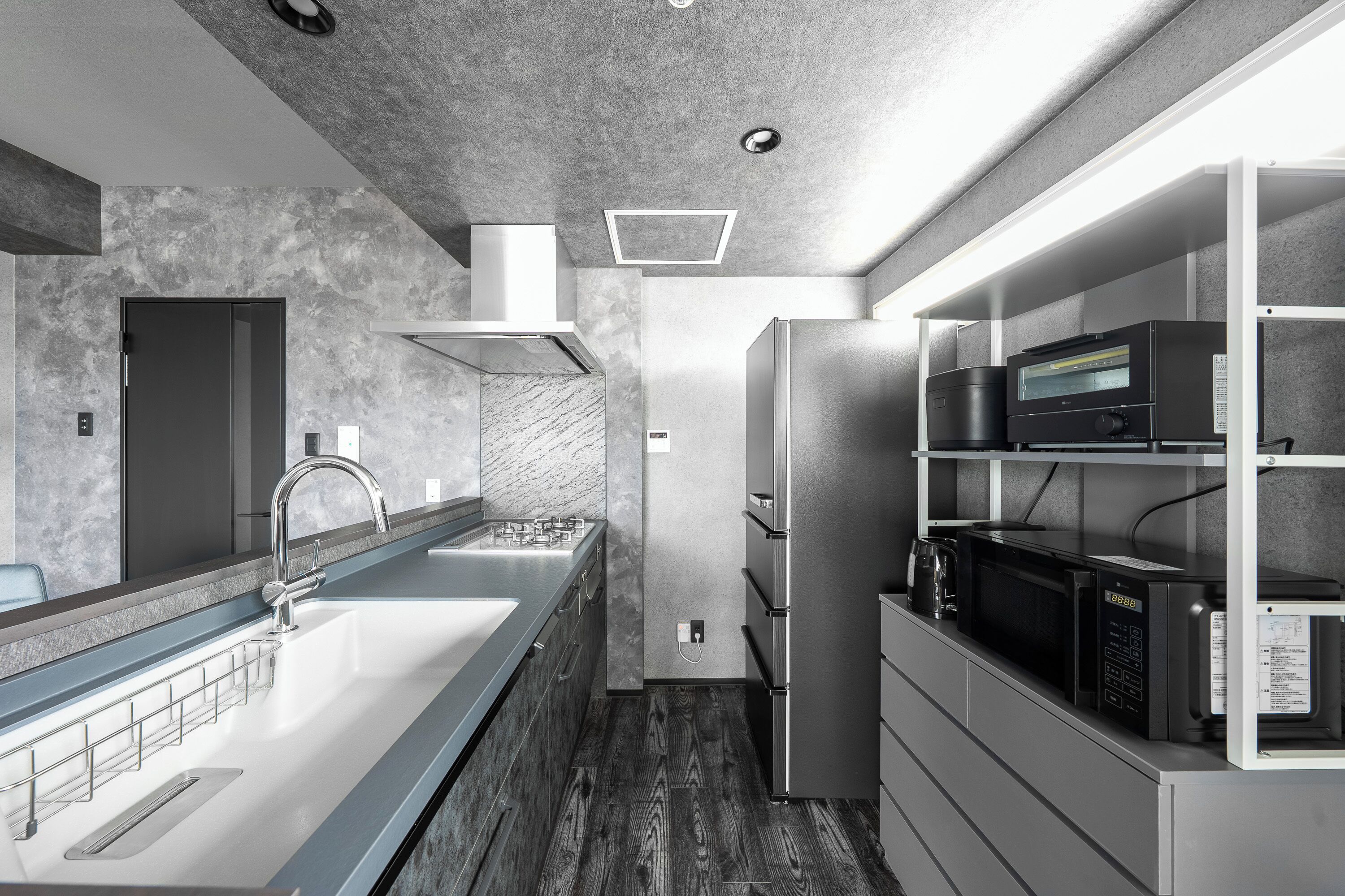 A modern kitchen with a stainless steel sink, a built-in microwave, and a range hood.
