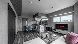 A modern living room with a sofa, a coffee table, and a TV displaying 'NETFLIX'. - J-STAR 901 (Sapporo)