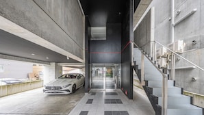 A modern building with a car parked in a covered area, a staircase, and a tiled floor. - J-STAR 901 (Sapporo)