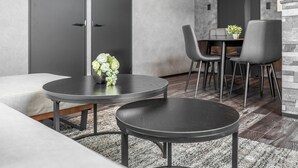 A modern living room with two round tables, a sofa, and a dining area with chairs and a small table. - J-STAR 901 (Sapporo)