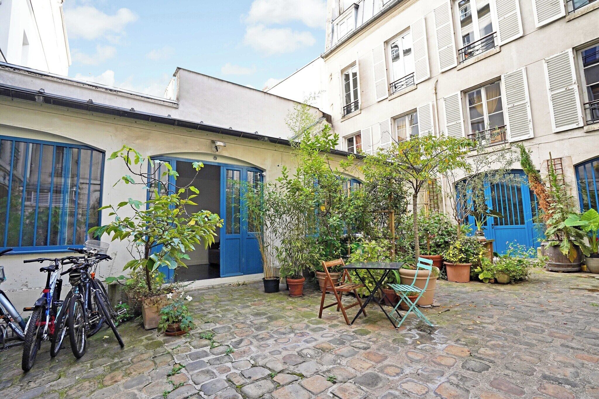 Ein Innenhof mit Tisch, Stühlen, Blumentöpfen und Fahrrädern.