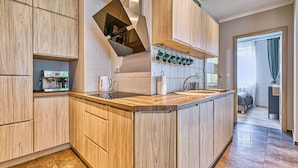 Una cocina moderna con armarios de madera, horno empotrado, cafetera y pileta de acero inoxidable.