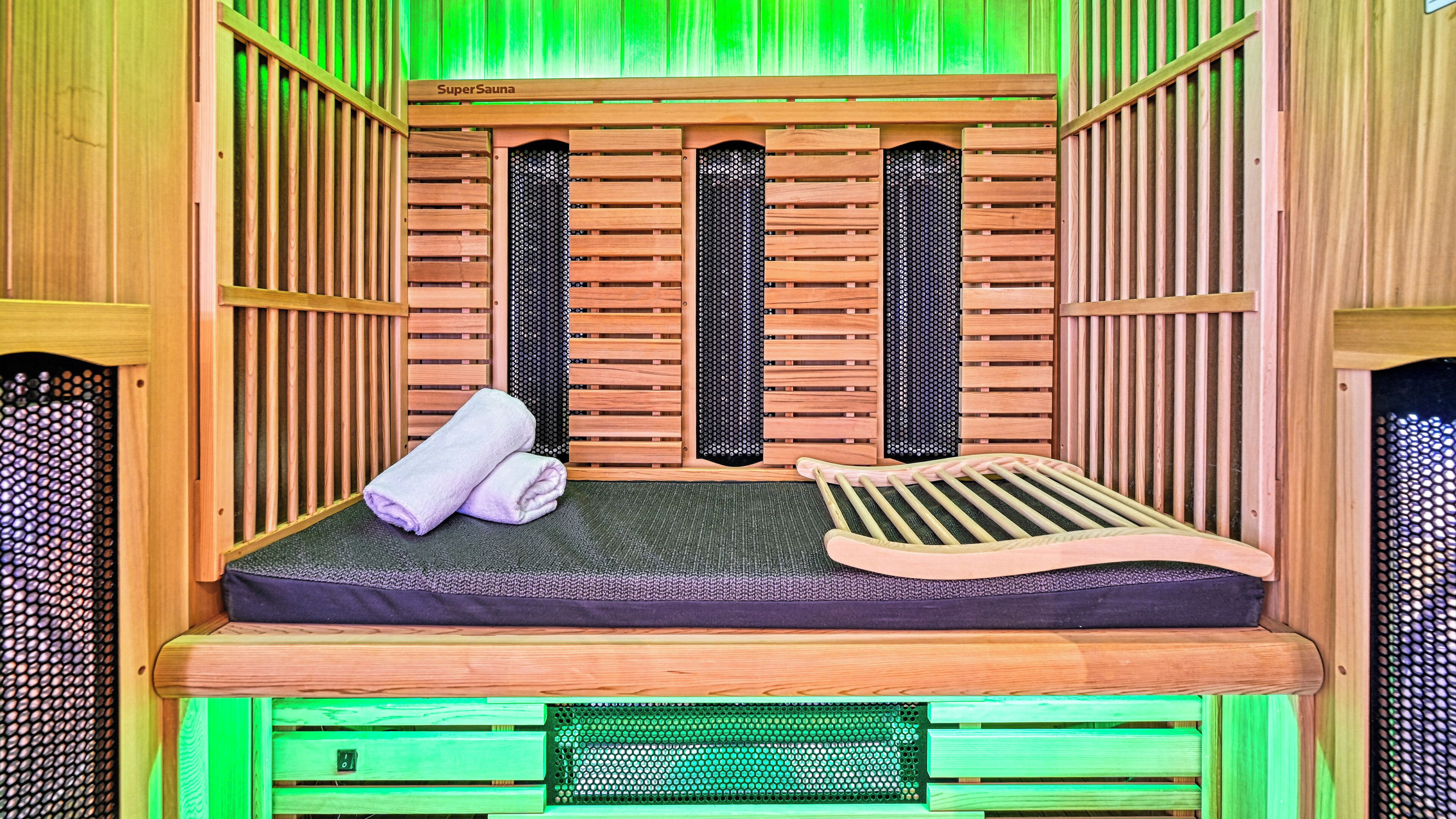 A sauna with a wooden bench, a towel, and a mat.