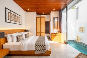 A modern bedroom with a wooden ceiling, a large bed with patterned bedding, a bedside table, a nightstand, a wooden dresser, a mirror, and a view of a swimming pool.