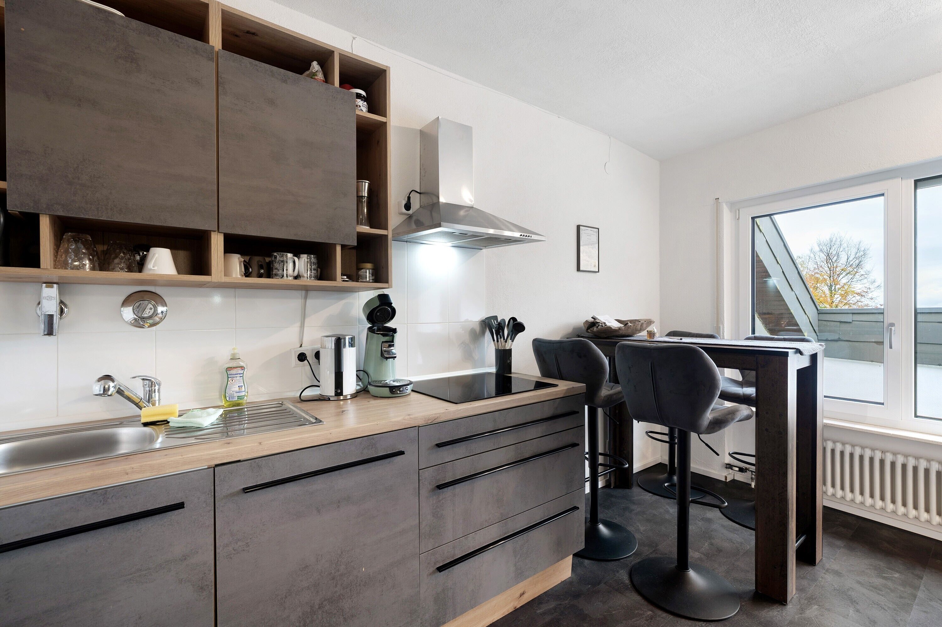 A modern kitchen with a built-in stove, a coffee maker, and a window with a view.