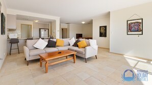 A modern living room with a sofa, coffee table, and a dining area in the background. - Canal apartment with Jetty (Halls Head)