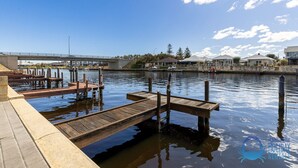 A waterfront dock area with wooden docks and a bridge in the background. - Canal apartment with Jetty (Halls Head)