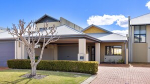 A modern two-story house with a garage, a well-maintained lawn, and a paved driveway. - Canal apartment with Jetty (Halls Head)