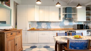 A modern kitchen with white cabinets, a wooden dining table, and a blue patterned floor. - Caletta Nest 88 by Klodge – Sea view & pool (Porto Rotondo)