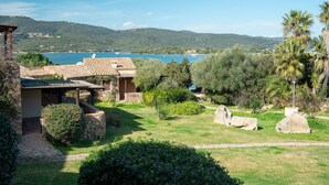 Una villa rústica con fachada de piedra, techo de tejas y vistas a un lago y montañas.