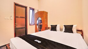 Une chambre d’hôtel avec un lit, une armoire en bois, une porte et un appareil de climatisation.