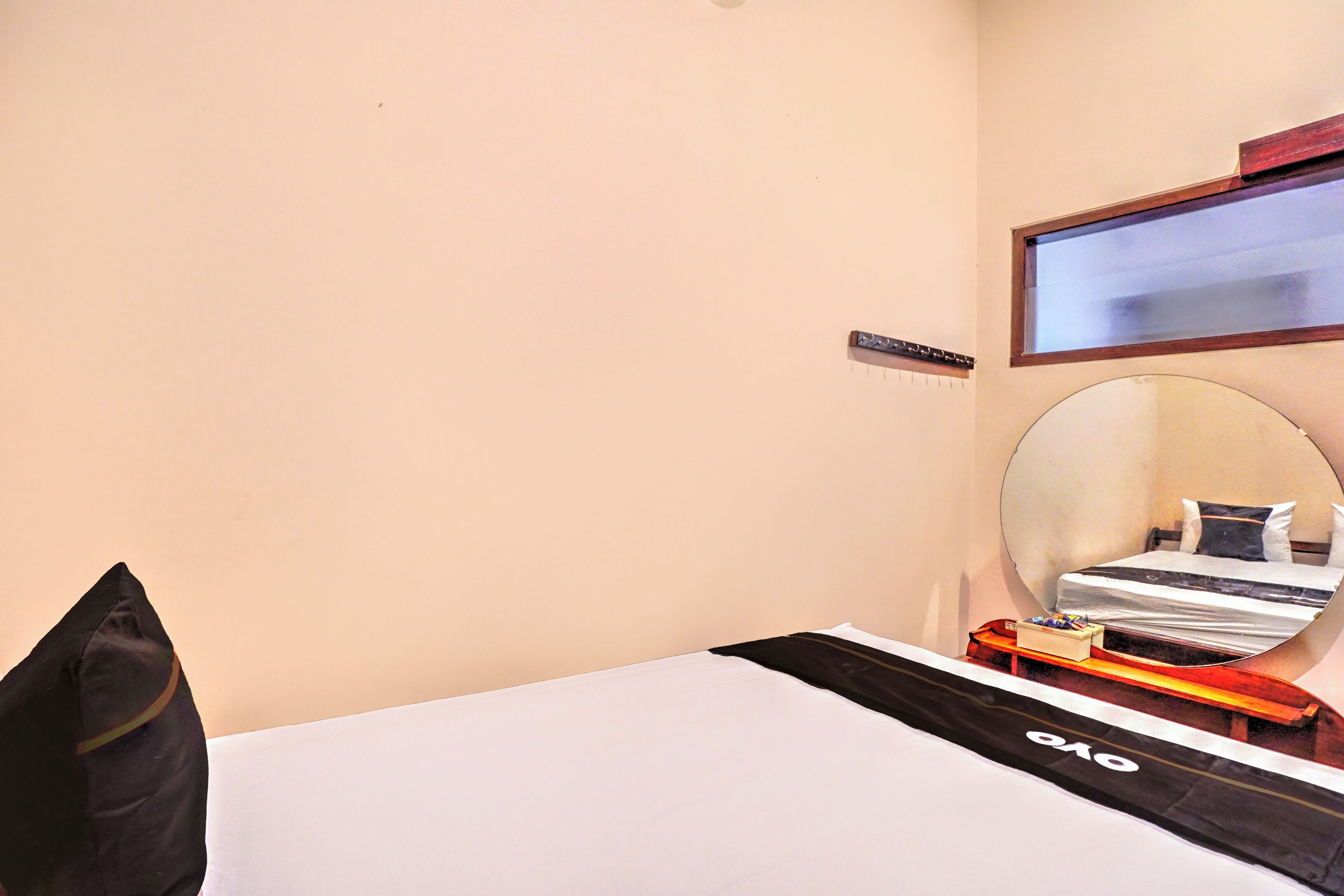 A hotel room with a bed, a mirror, a small table, and a sign on the wall.