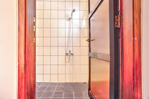 Ein Badezimmer mit Dusche, gefliesten Wänden und einer Holztür.