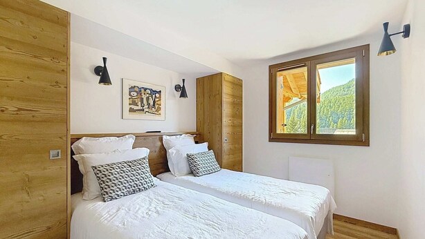 Une chambre avec deux lits, des murs en bois, une fenêtre donnant sur un beau paysage et un tableau accroché au mur.