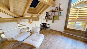 Un intérieur moderne avec un plafond de style industriel, un plancher en bois et un coin salon comprenant un canapé blanc et un pouf.