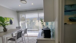 A modern kitchen with a dining area, large windows, and a potted plant. - Ace on Par - Central Dunsborough (Dunsborough)