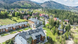Et boligområde med moderne huse, en stor bygning med fladt tag og et bjergrigt landskab i baggrunden.