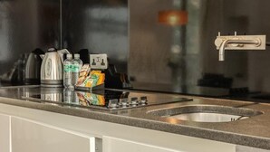 A kitchen with a stainless steel sink, a kettle, and a coffee maker.