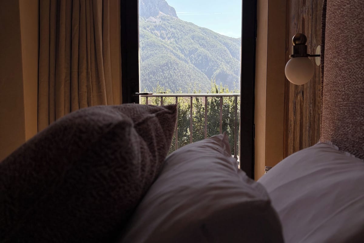 A bedroom with a view of a mountain through a window.