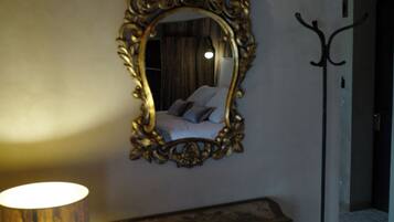 A bedroom with a large ornate mirror, a bedside lamp, and a vintage dresser.