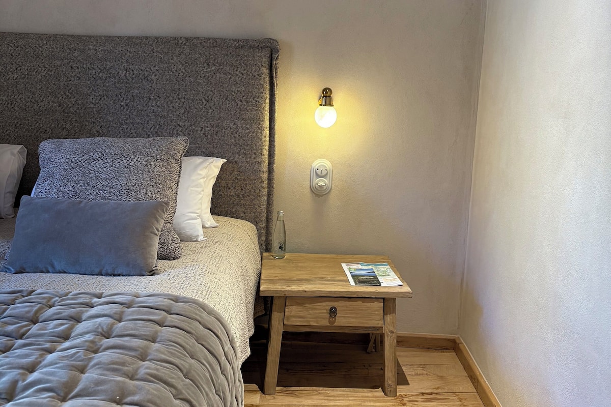A bedroom with a bed, a bedside table with a lamp, a nightstand, and a rug.