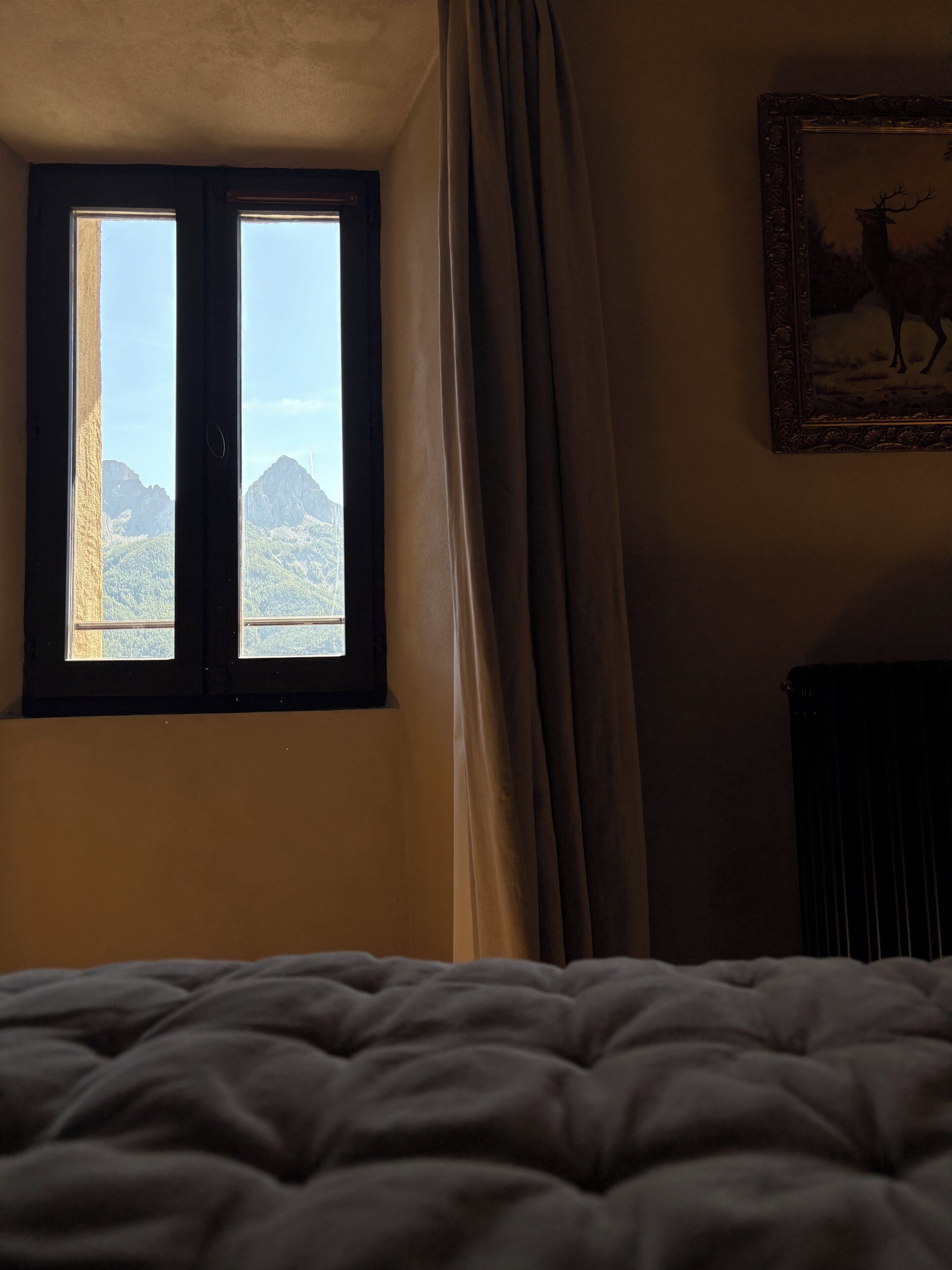 Una habitación con una cama, una ventana con cortinas y un cuadro en la pared.