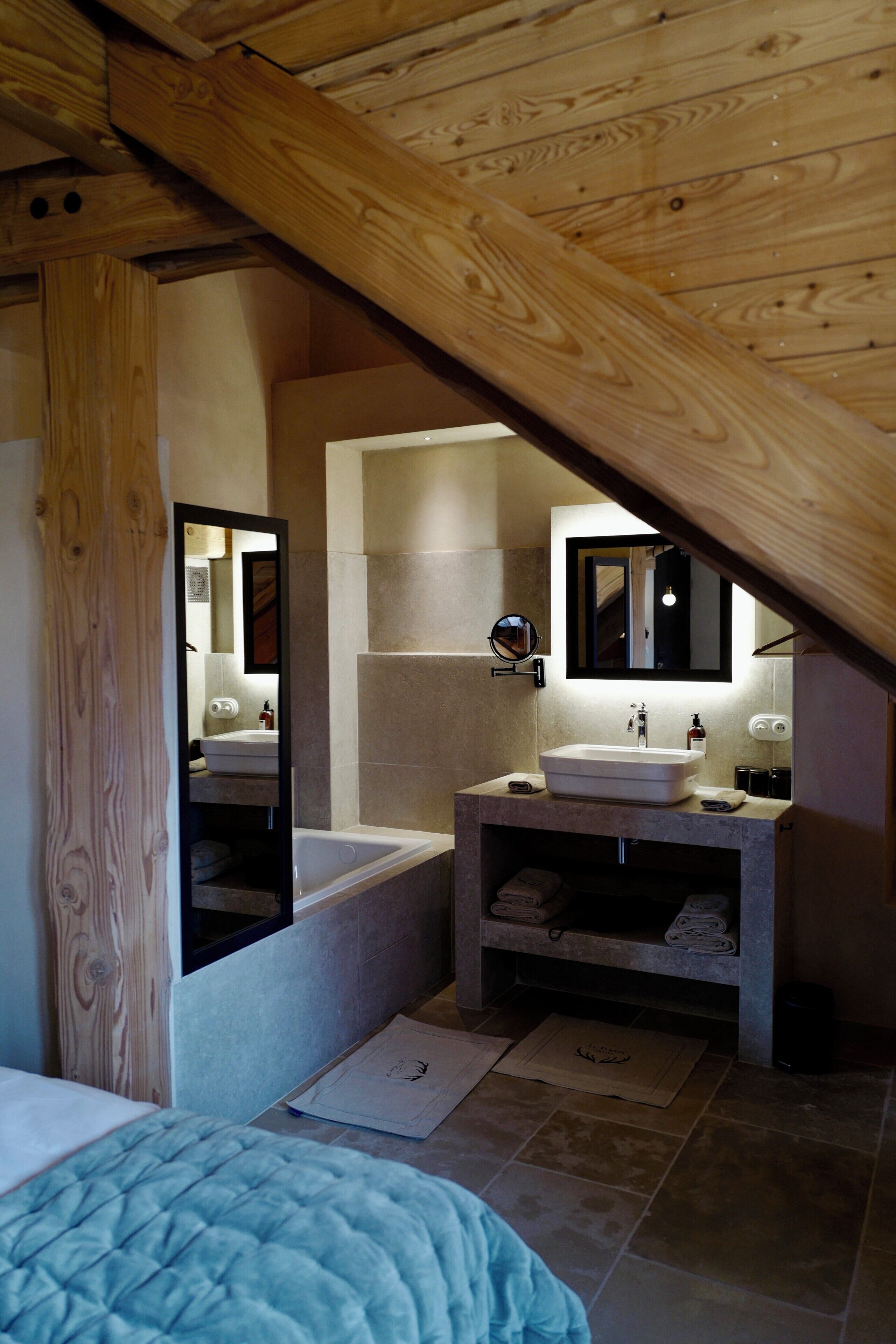 A modern bathroom with a wooden ceiling, a large mirror, a bathtub, and a sink.